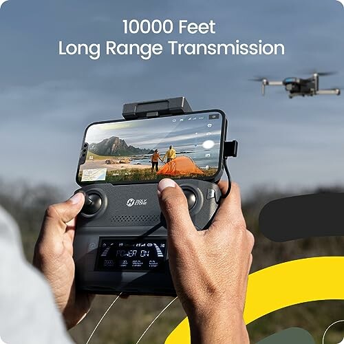 Hands holding a drone controller with a smartphone, drone flying in the background.